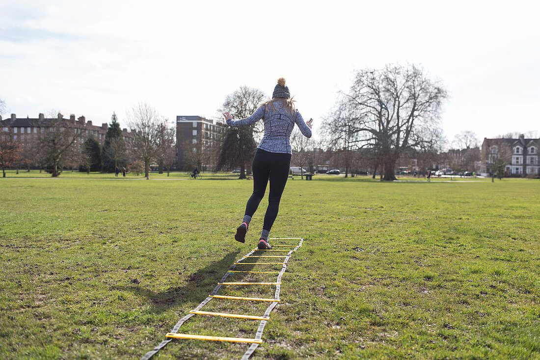 Woman exercising, doing speed ladder drill in sunny park