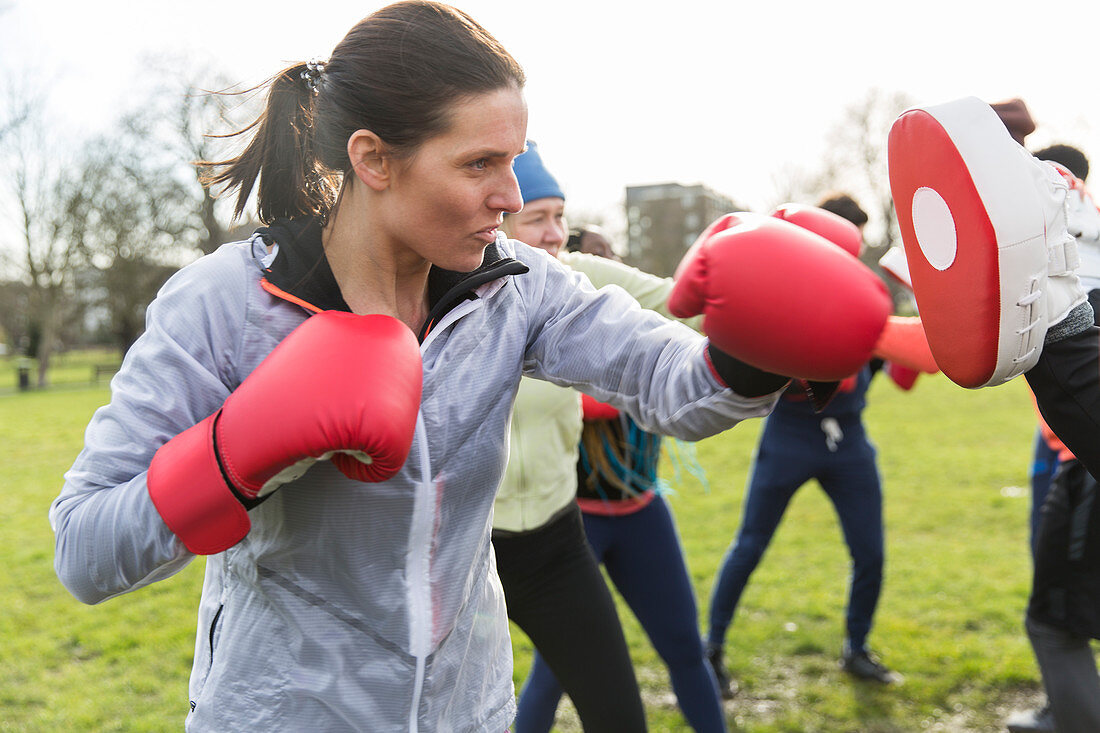 Determined, tough woman boxing in park