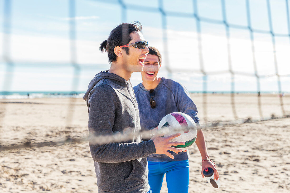 Happy male friends playing beach volleyball