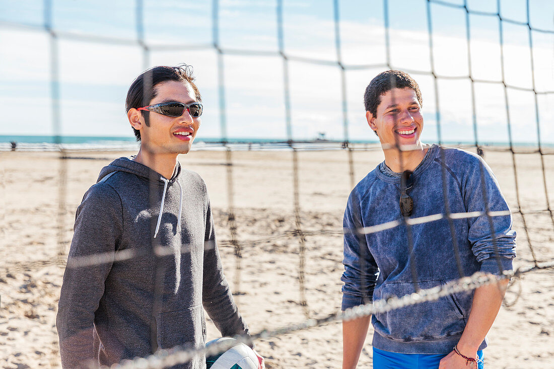 Smiling men playing beach volleyball