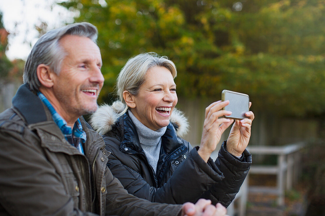 Happy mature couple using camera phone in park