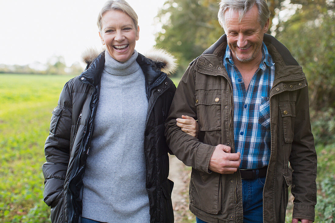Happy mature couple walking arm in arm in park