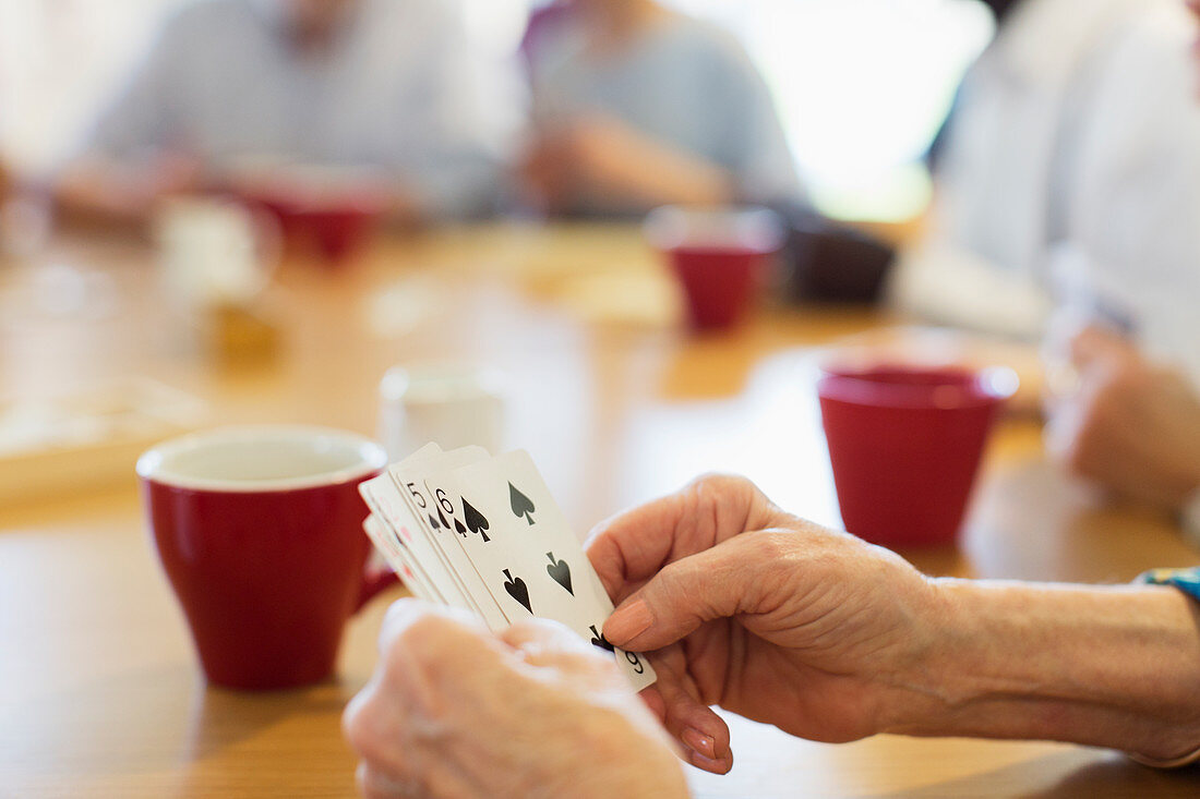 Close up senior woman playing cards with friends