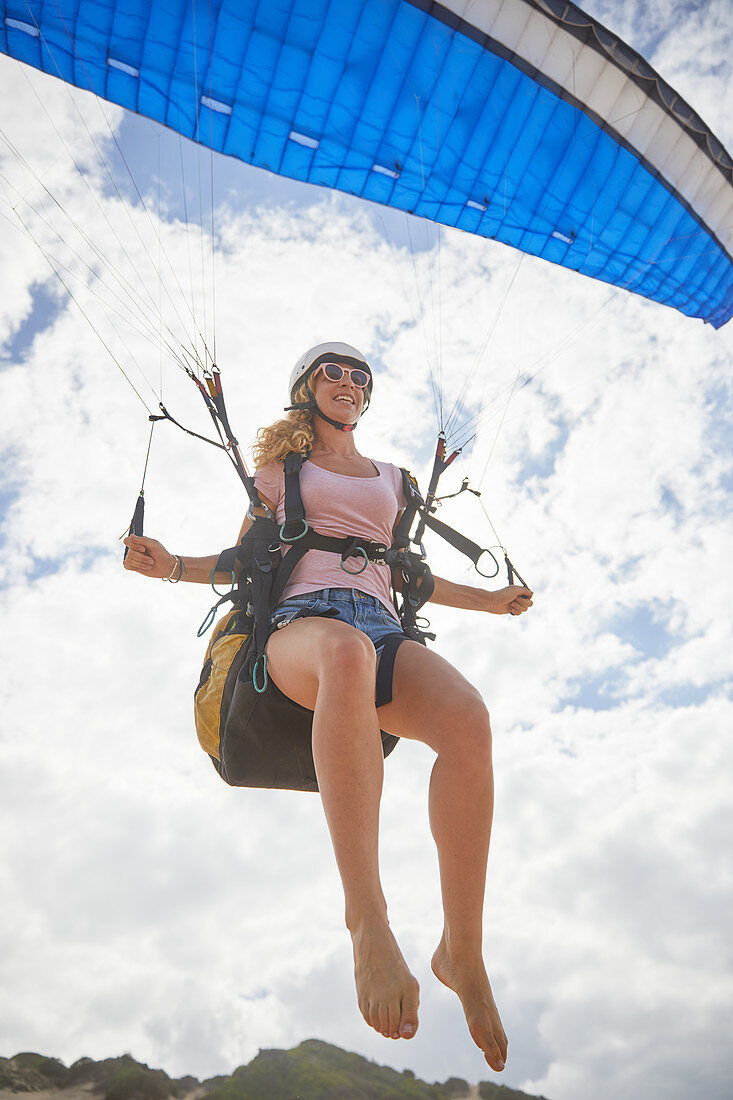 Smiling female paraglider mid-air