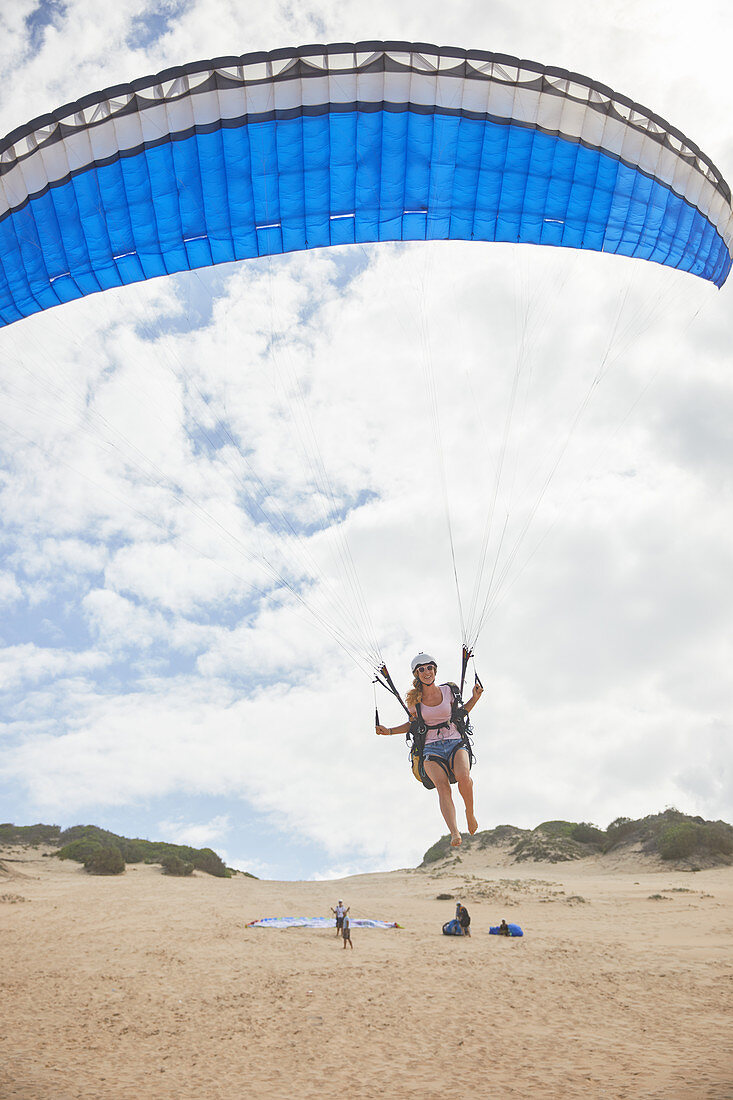 Female paraglider with parachute taking off