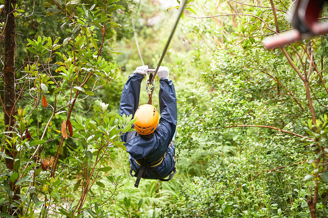 Woman zip lining among trees in woods