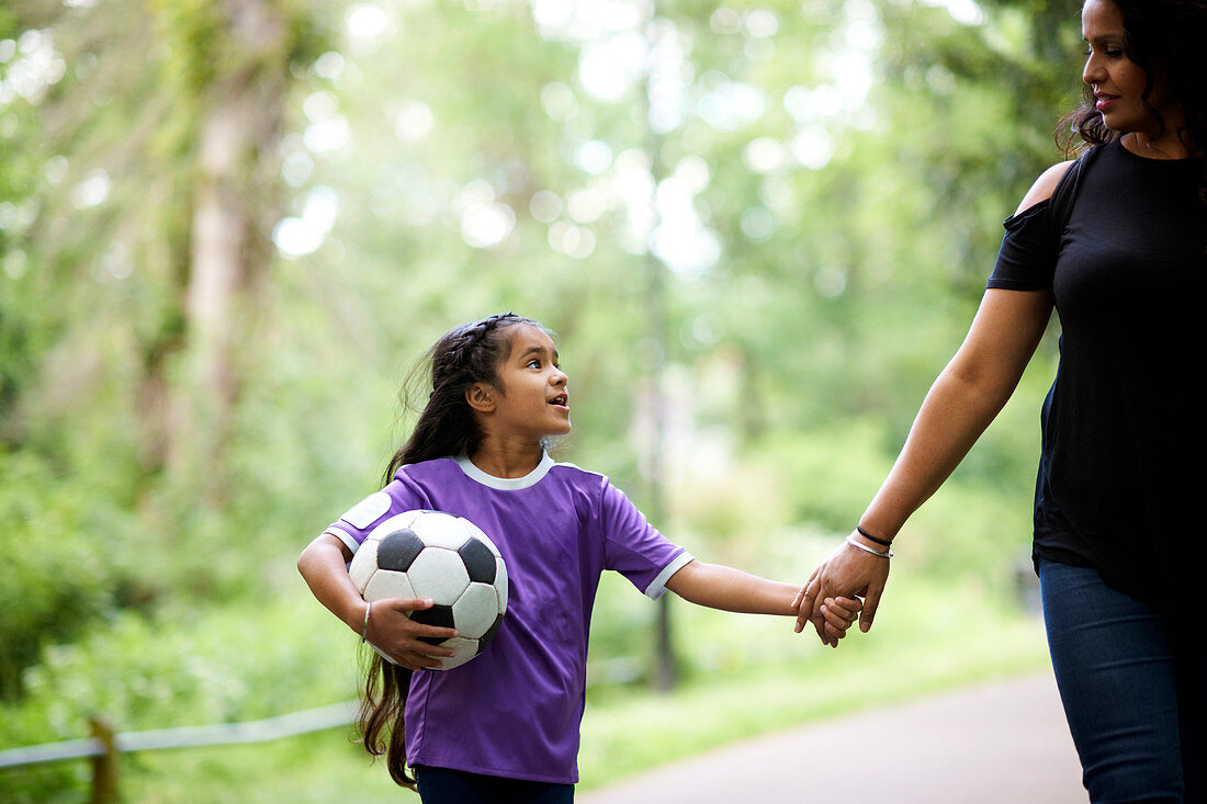 Mother and daughter with ball holding hands