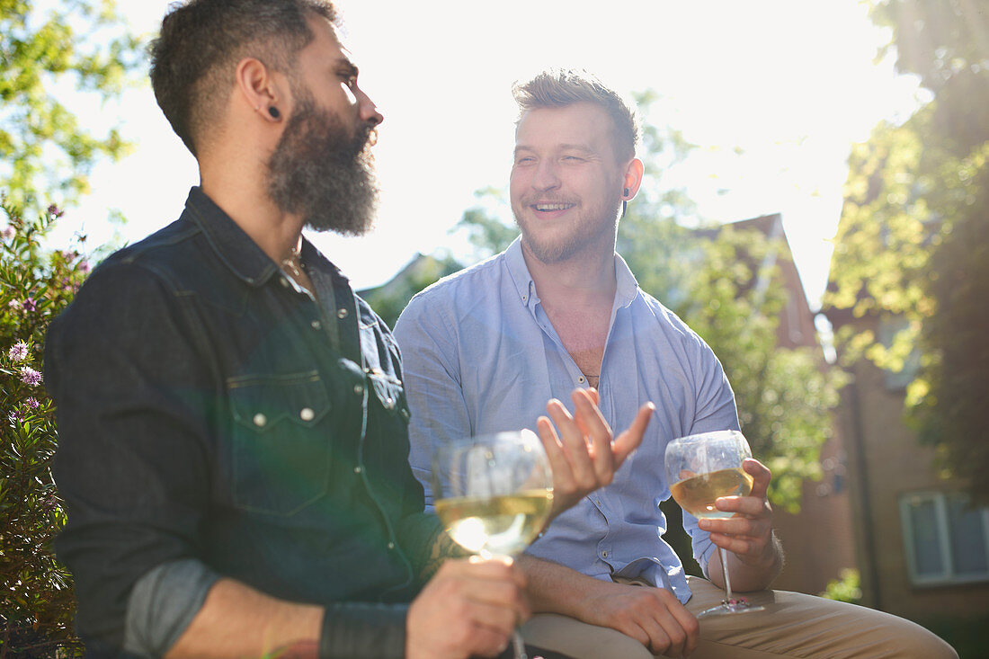 Smiling male gay couple drinking white wine