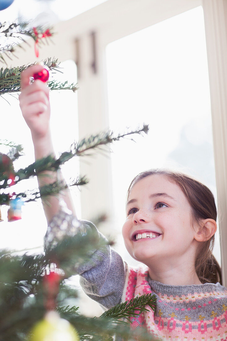 Girl touching ornament on Christmas tree
