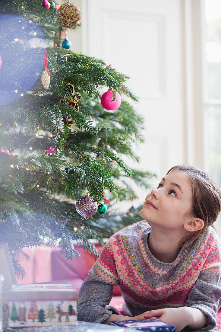 Curious girl with gift looking up tree