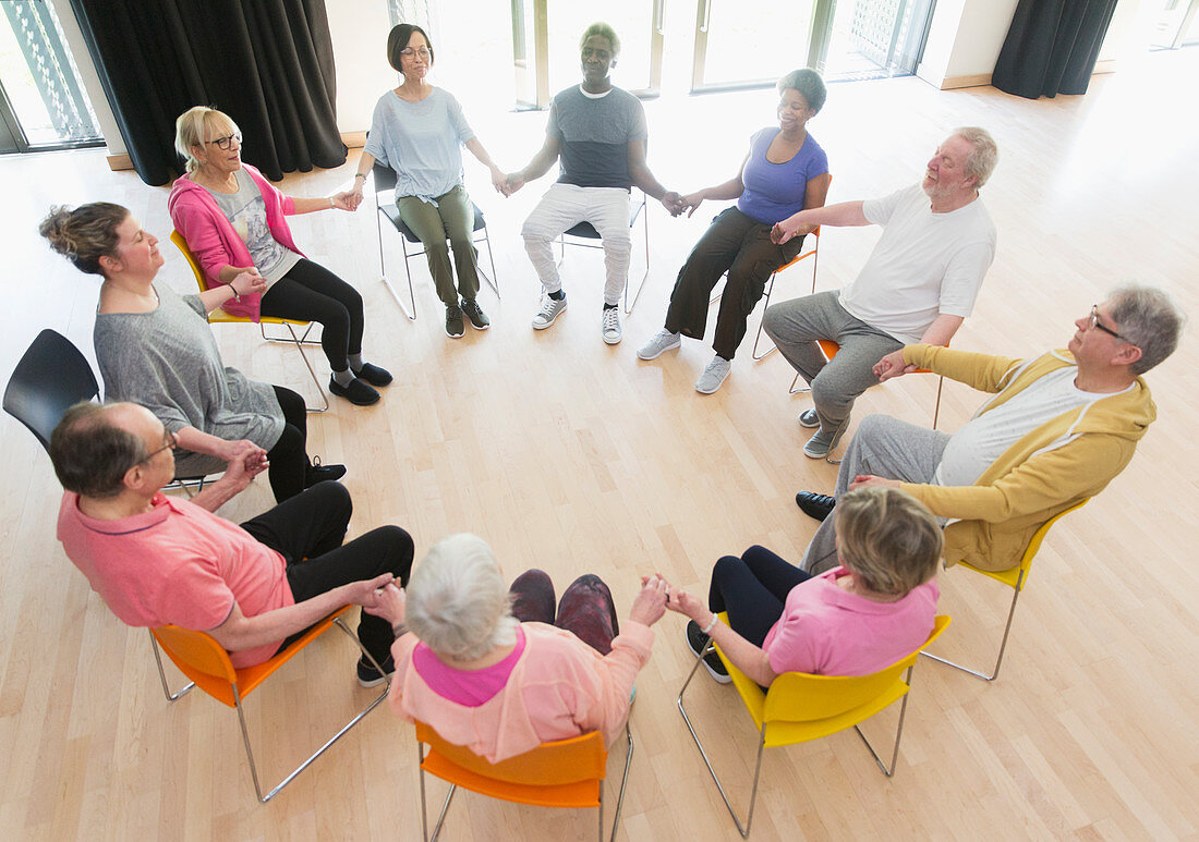 Active seniors holding hands in circle, meditating