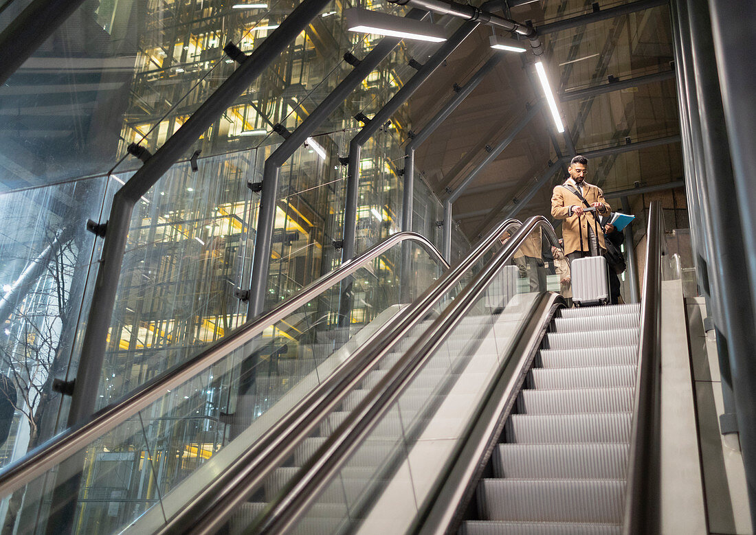 Businessman with suitcase on urban escalator