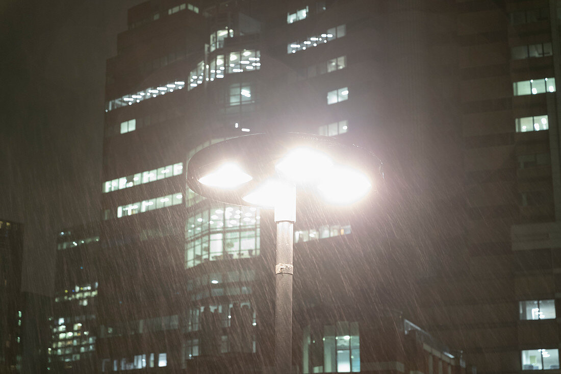 Rain falling around streetlamp at night