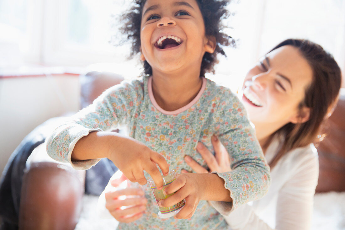 Playful mother and daughter laughing