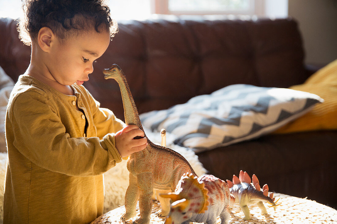 Innocent boy playing with dinosaur toys
