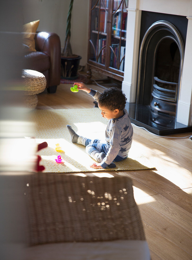 Toddler boy in pyjamas playing with toys on floor
