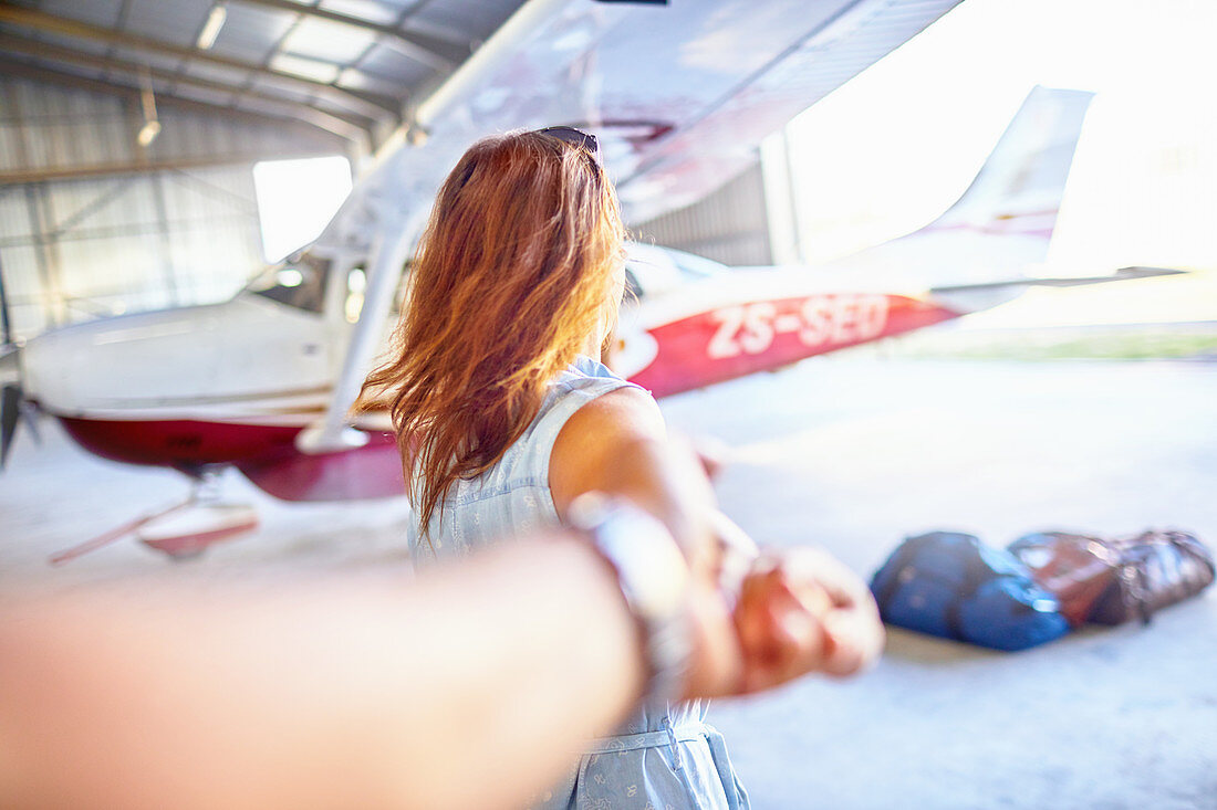 Woman leading man toward small airplane