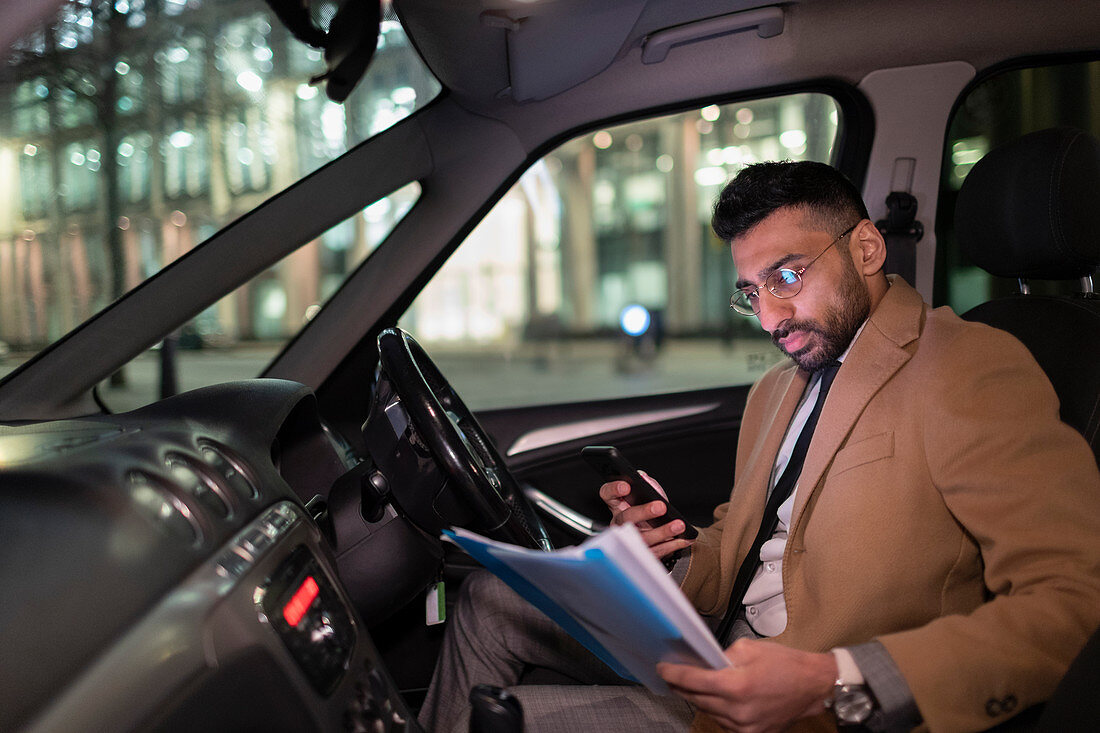 Businessman reading paperwork in car at night