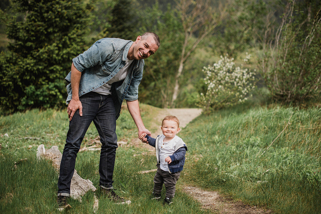Father and baby son walking on grassy path