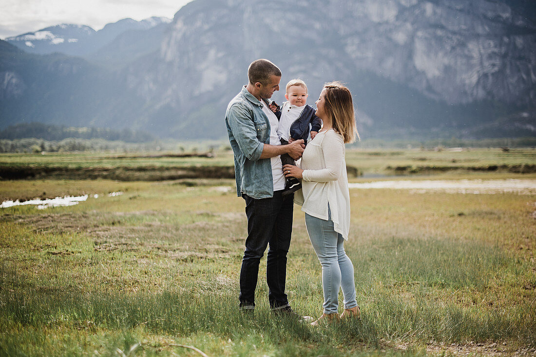 Parents and baby son standing in rural field