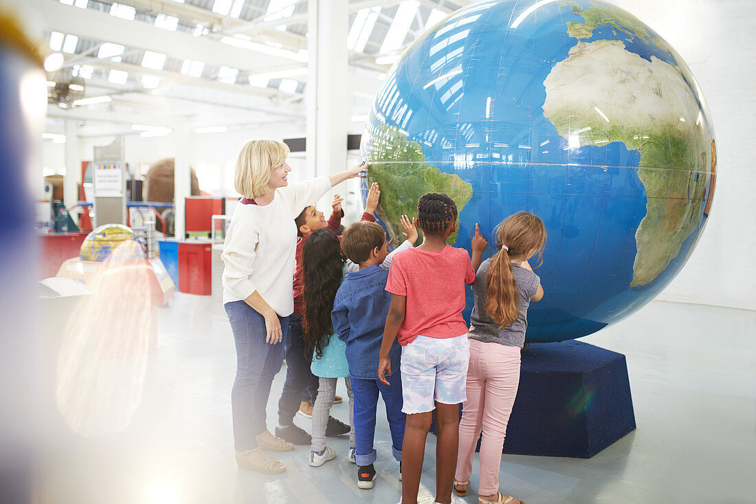 Teacher and students touching large globe