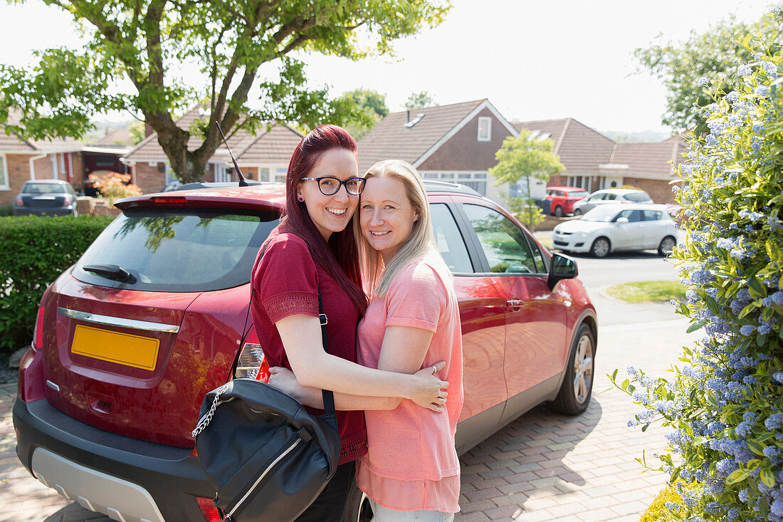 Lesbian couple hugging in driveway