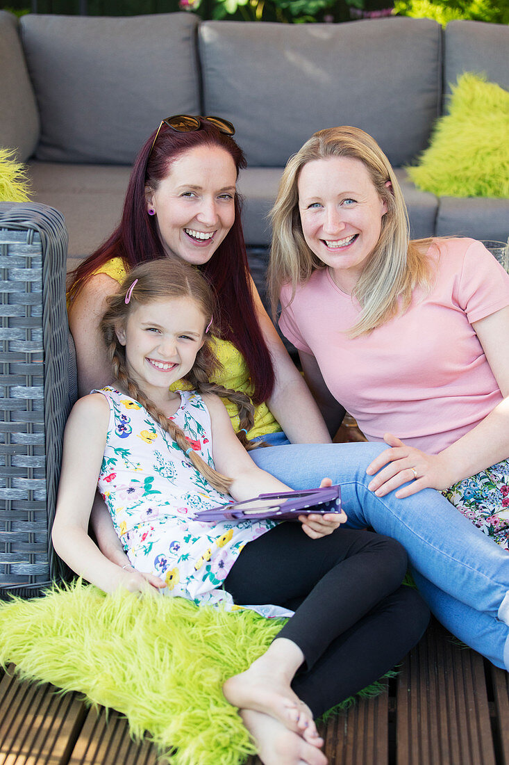 Lesbian couple and daughter relaxing on patio