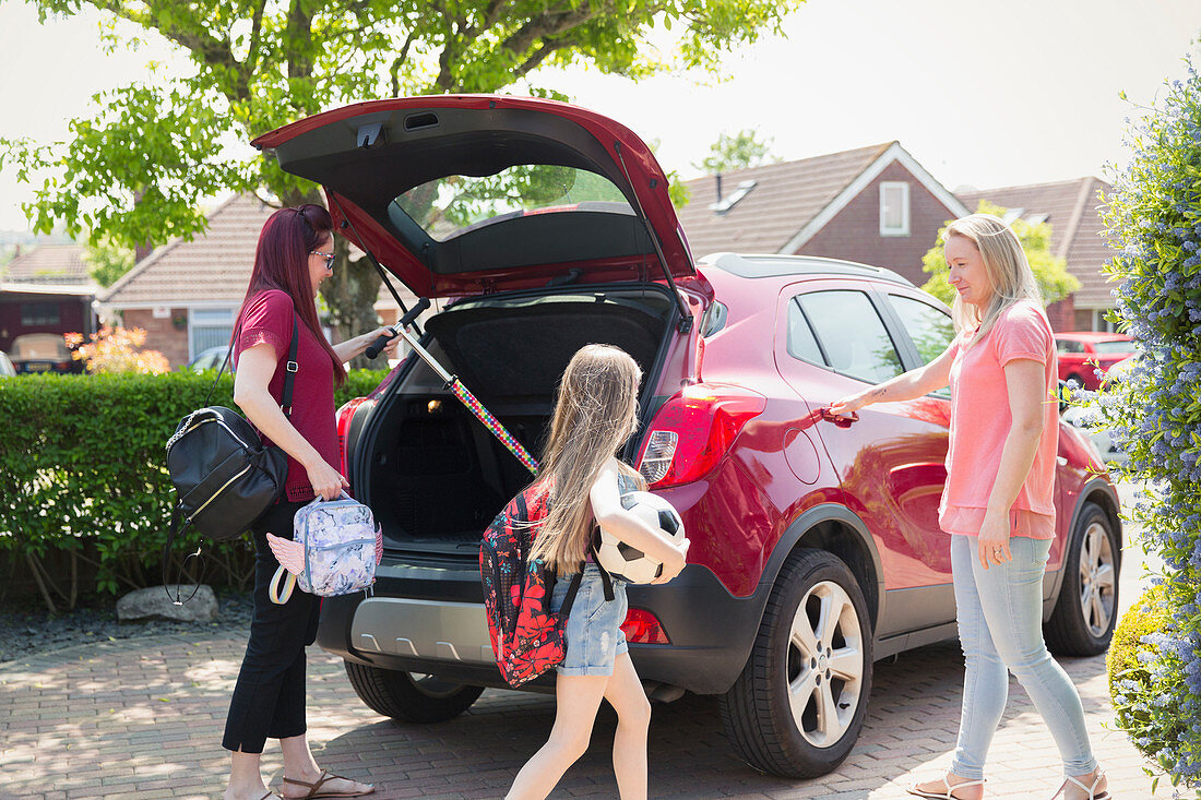 Lesbian couple and daughter loading car for school