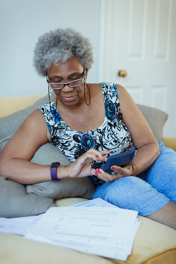 Senior woman with calculator reviewing bills
