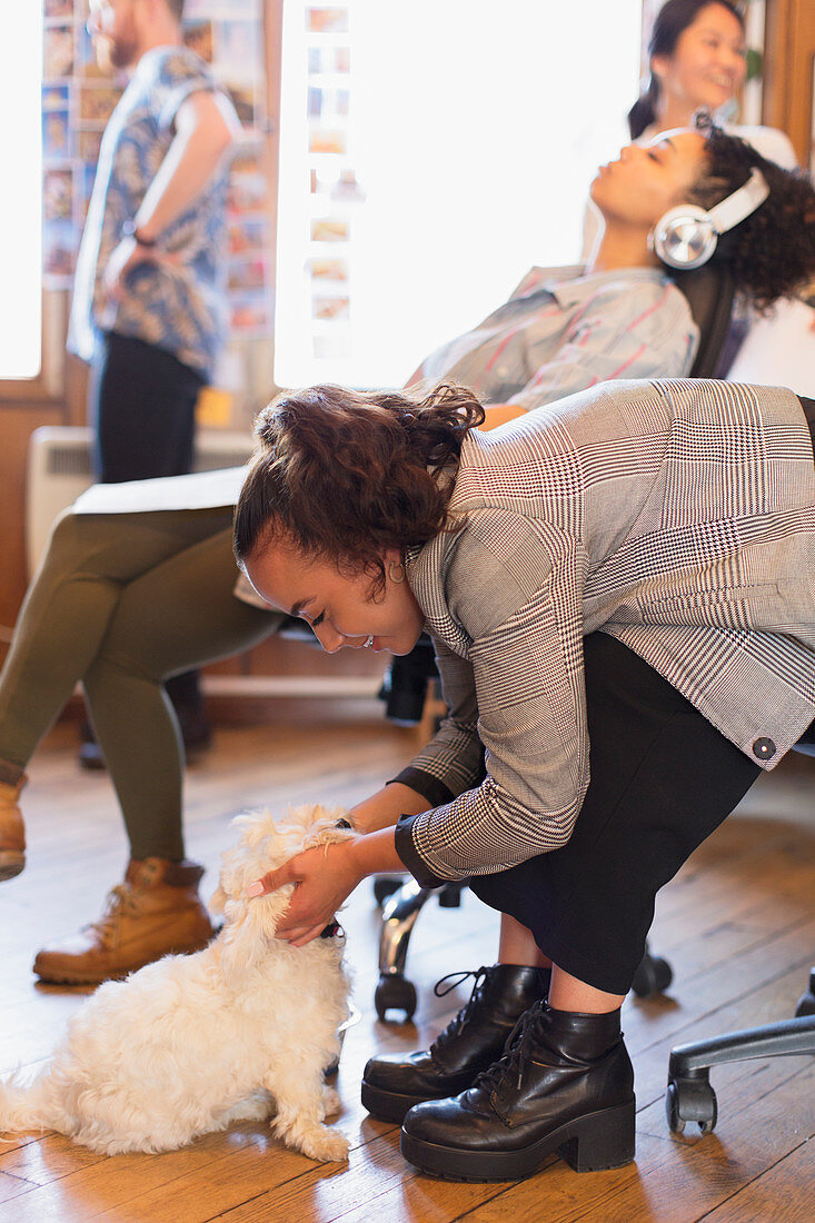 Creative businesswoman petting cute dog in office