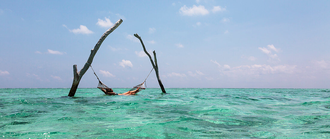 Young woman laying in hammock over blue ocean