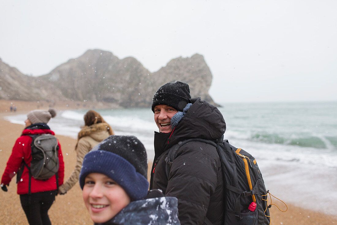 Portrait father and son walking on snowy beach