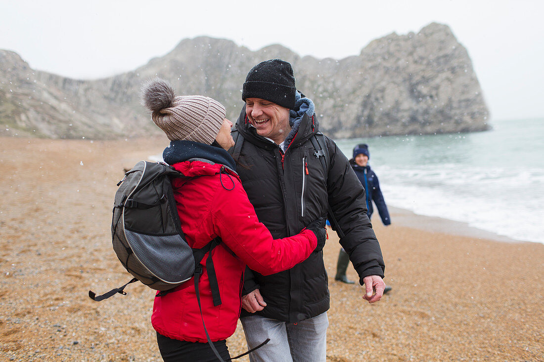Couple in warm clothing on snowy winter beach