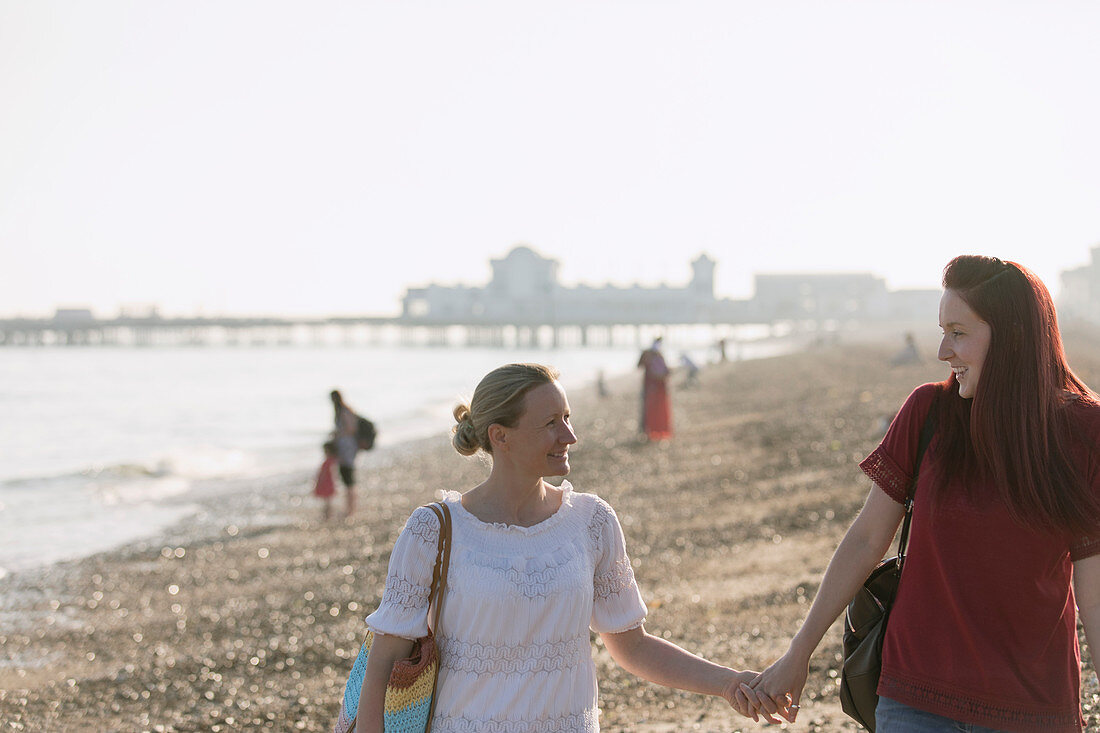 Lesbian couple holding hands on beach