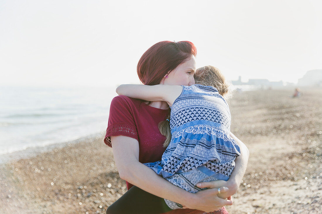 Mother holding daughter on beach