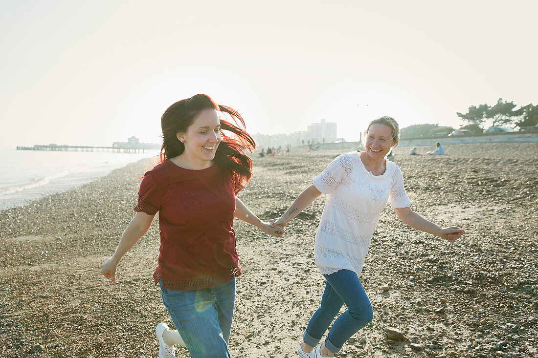 Playful lesbian couple running on beach