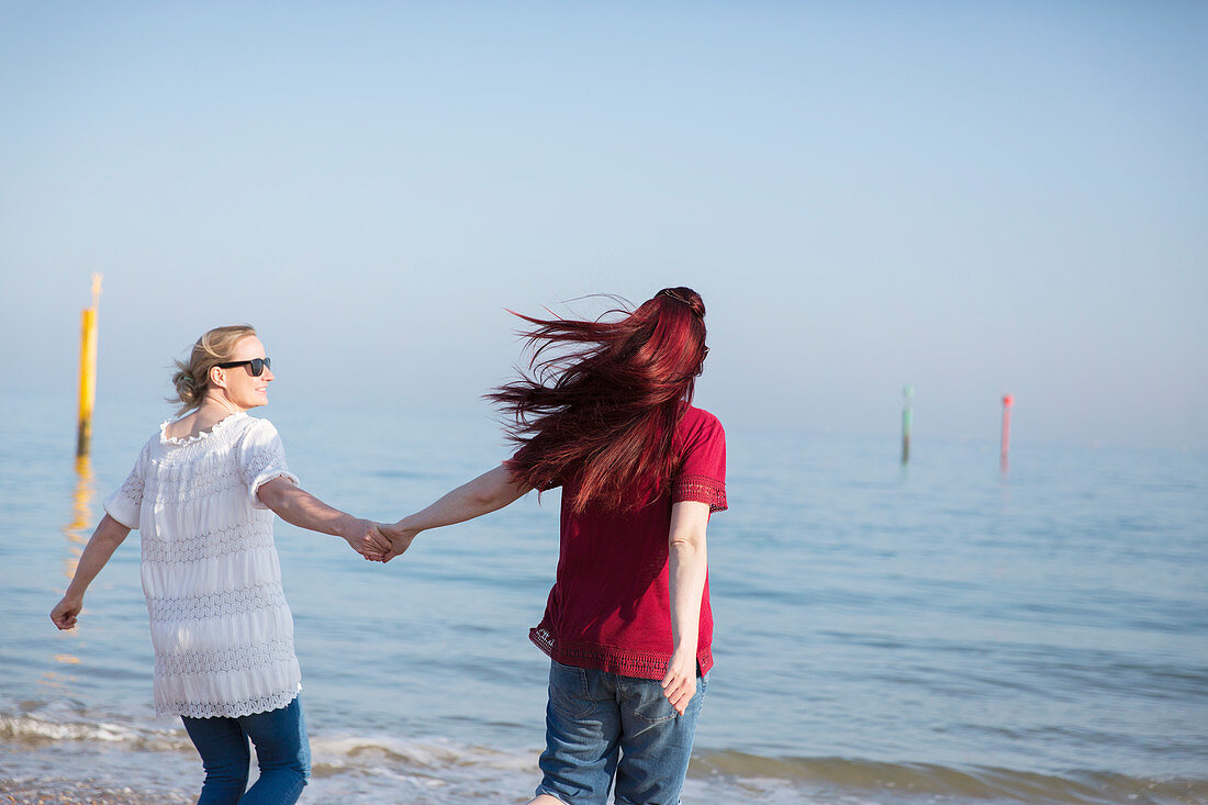 Lesbian couple holding hands on ocean beach
