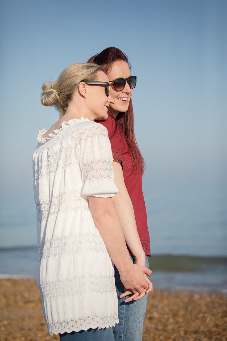 Lesbian couple holding hands on beach