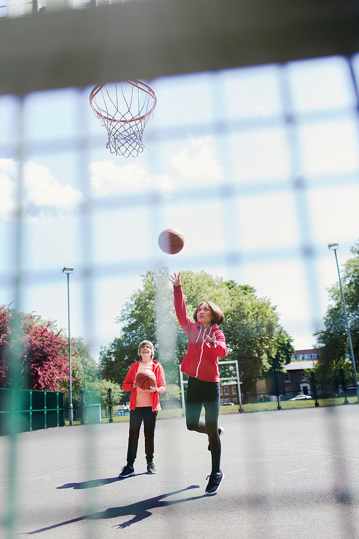Active senior women playing basketball in park