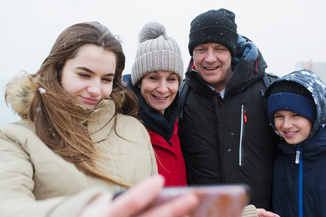 Snow falling on smiling family taking selfie