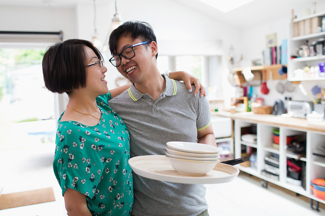 Couple hugging, doing dishes in kitchen