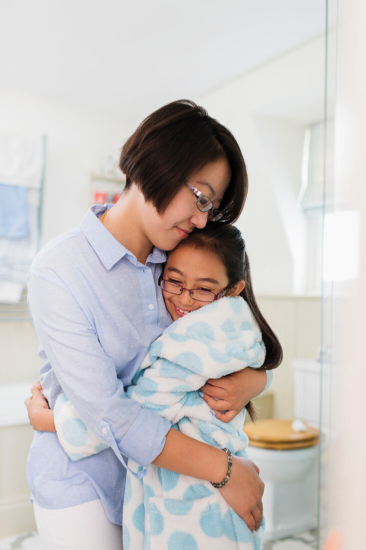 Mother and daughter hugging in bathroom