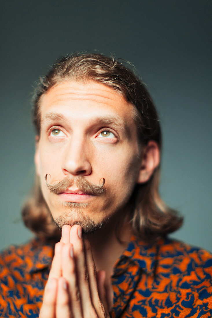 Portrait young man with handlebar moustache praying