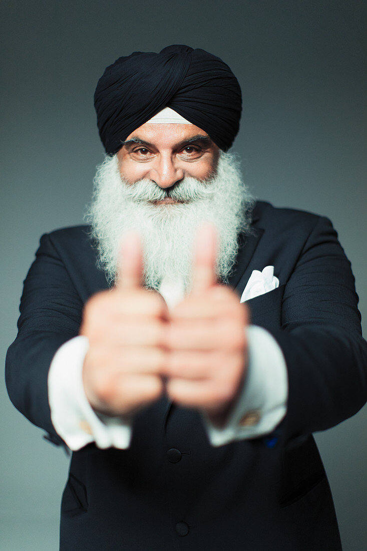 Senior man wearing turban, gesturing thumbs-up
