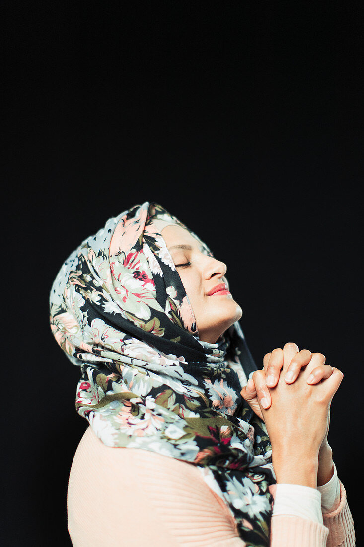 Serene woman in floral hijab praying