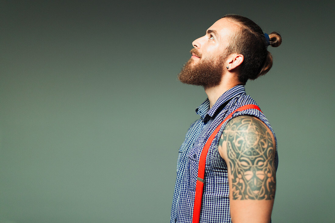 Curious hipster man with beard and shoulder tattoo