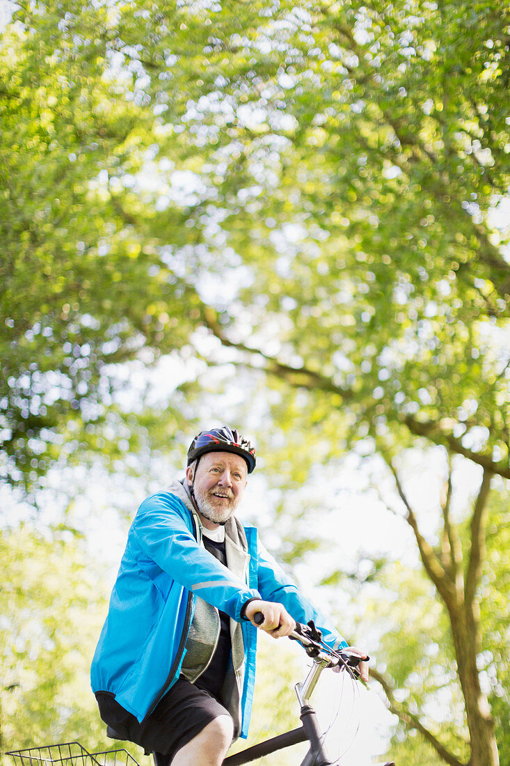 Portrait active senior man riding bike in park