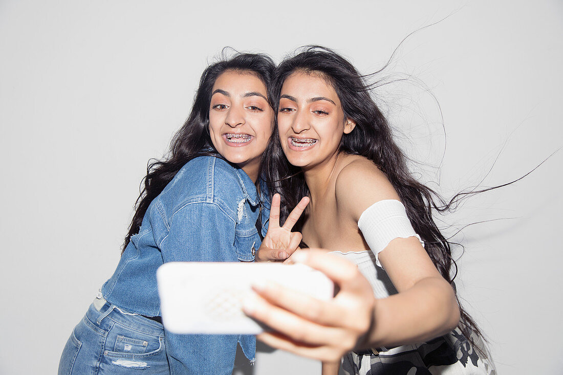 Carefree teenage twin sisters taking selfie