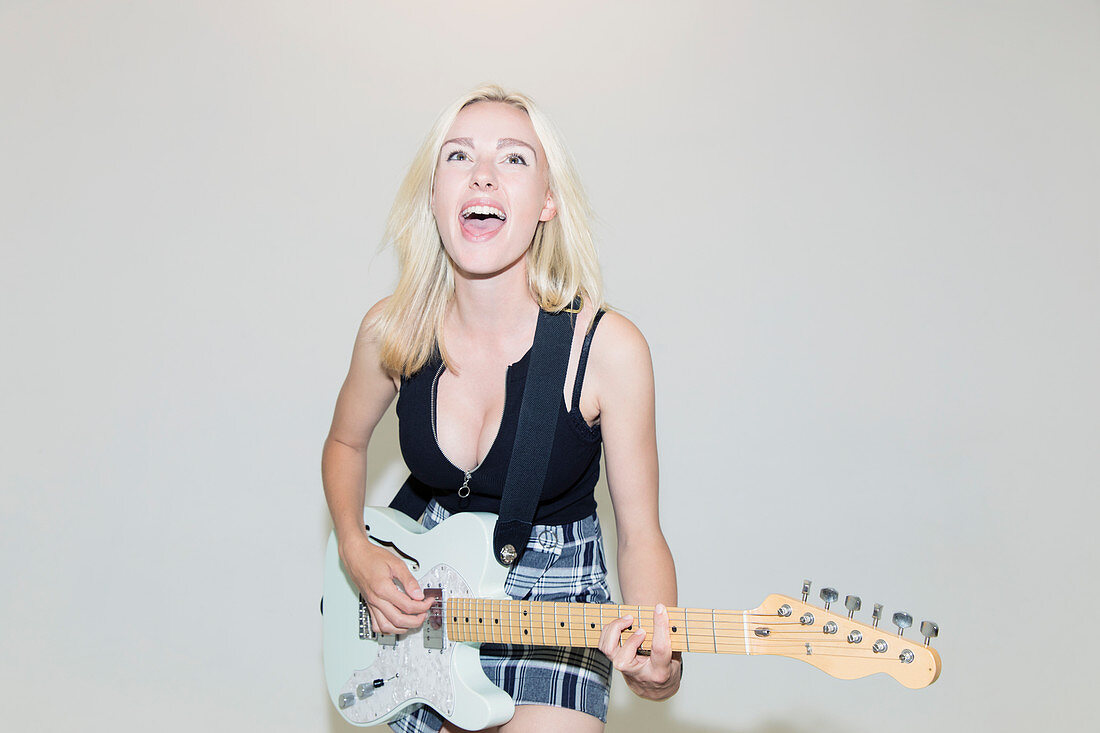 Exuberant young woman playing electric guitar