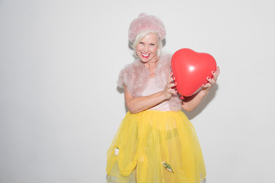 Senior woman holding heart-shape balloon